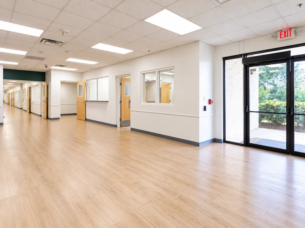 Existing condition: the entrance area inside the main building, with a glass entry door, an interior window and a long corridor.