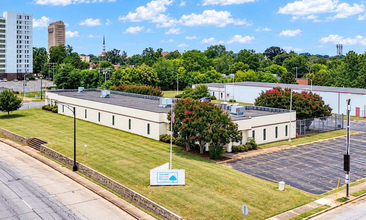 Aerial view from South Church Street of the 325 South Church campus: the single-story main building behind a lawn, the metal second building beyond it, and the paved lot to the right.